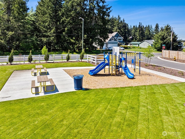 communal playground featuring a yard and fence