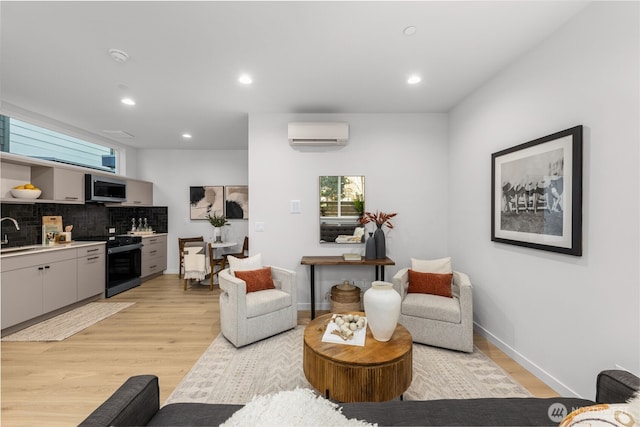 living area featuring baseboards, recessed lighting, a wall mounted air conditioner, and light wood-style floors