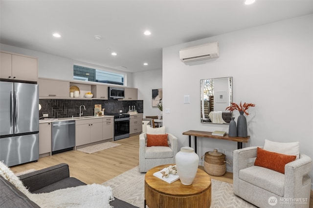 kitchen with tasteful backsplash, a wall mounted air conditioner, stainless steel appliances, light wood-type flooring, and a sink