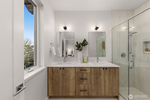 bathroom with double vanity, a stall shower, and a sink