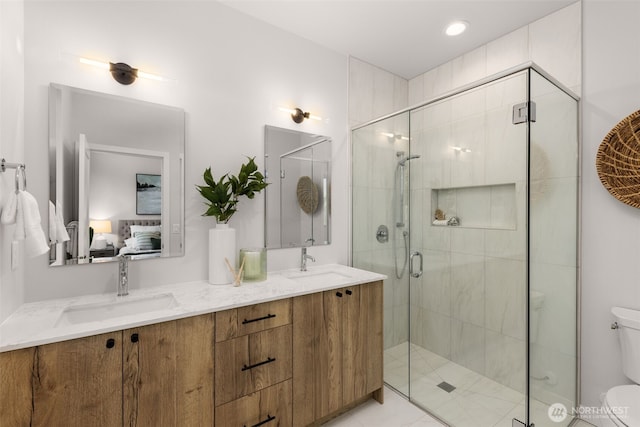 full bathroom featuring a stall shower, a sink, toilet, and ensuite bathroom