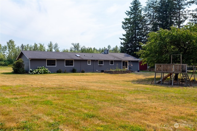 back of house with a yard and a playground