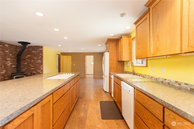 kitchen featuring sink, light hardwood / wood-style flooring, white appliances, and a wood stove