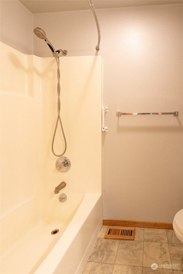 bathroom with shower / bathing tub combination, tile patterned floors, and toilet