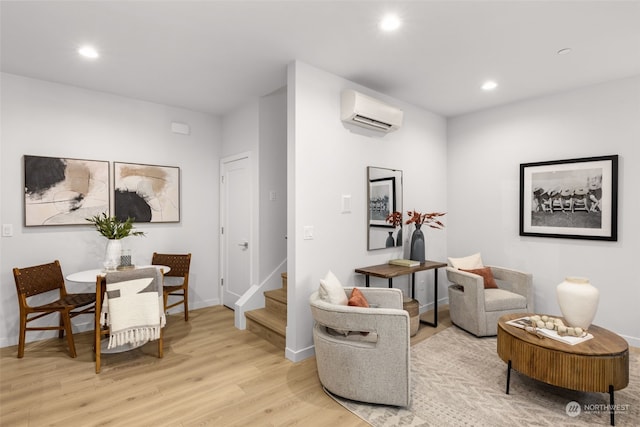 sitting room with a wall mounted air conditioner and light hardwood / wood-style floors