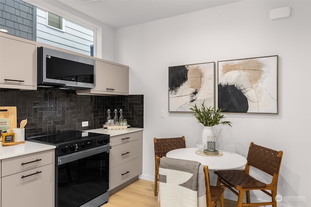 kitchen featuring light hardwood / wood-style floors, electric stove, and backsplash