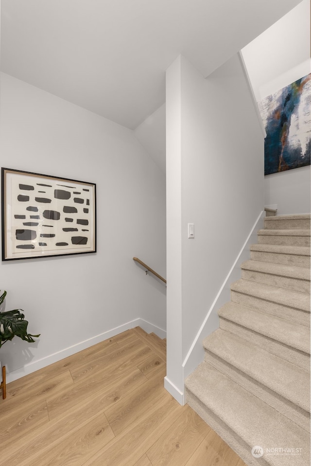 staircase featuring hardwood / wood-style flooring and vaulted ceiling