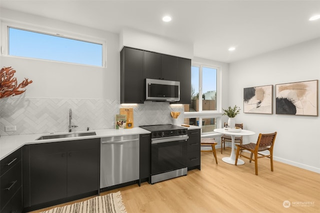 kitchen featuring sink, decorative backsplash, light hardwood / wood-style floors, and appliances with stainless steel finishes