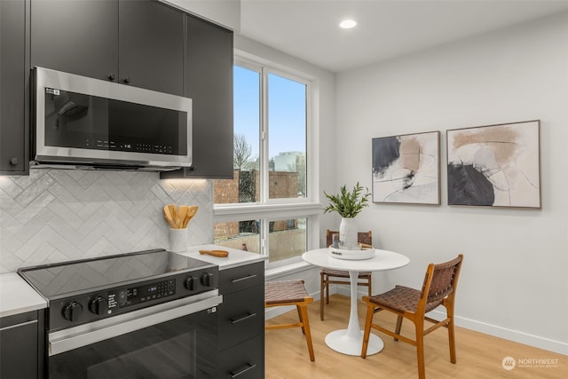 kitchen featuring light hardwood / wood-style flooring, electric range oven, and backsplash