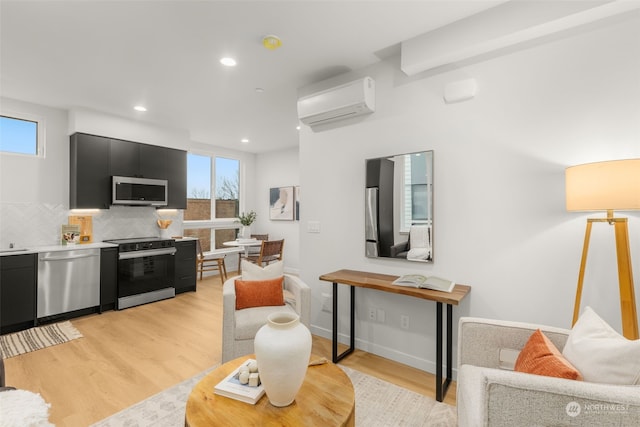 living room with a wall mounted AC and light hardwood / wood-style floors