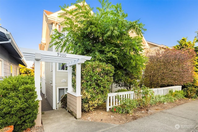 view of home's exterior with a pergola and fence