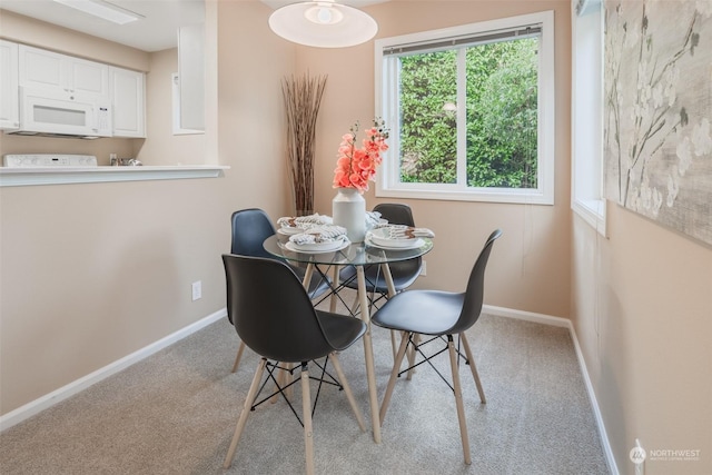 carpeted dining room featuring baseboards