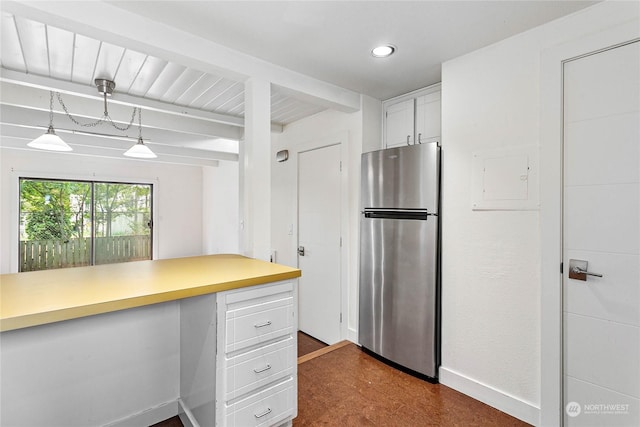 kitchen featuring stainless steel refrigerator, beamed ceiling, hanging light fixtures, and white cabinets