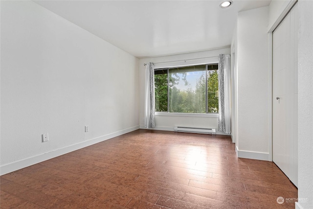 empty room with baseboard heating and dark hardwood / wood-style floors