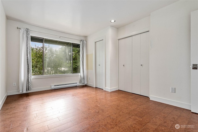 unfurnished bedroom with a baseboard heating unit and hardwood / wood-style flooring