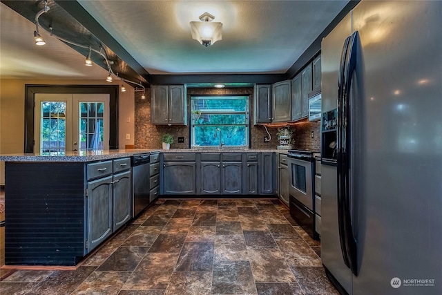 kitchen with tasteful backsplash, appliances with stainless steel finishes, kitchen peninsula, and french doors