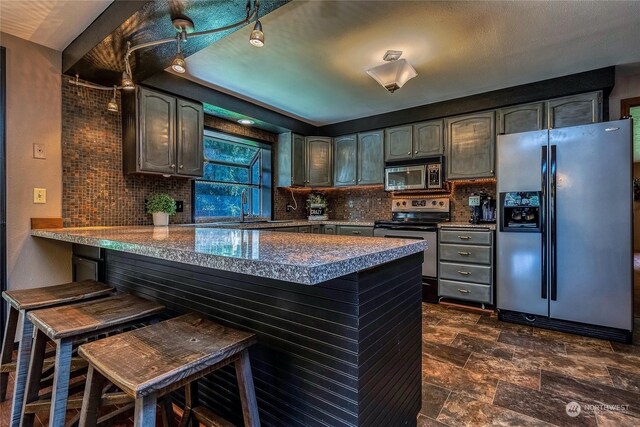 kitchen with backsplash, a breakfast bar, kitchen peninsula, and appliances with stainless steel finishes