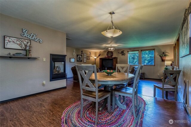 dining space with a multi sided fireplace and dark hardwood / wood-style floors