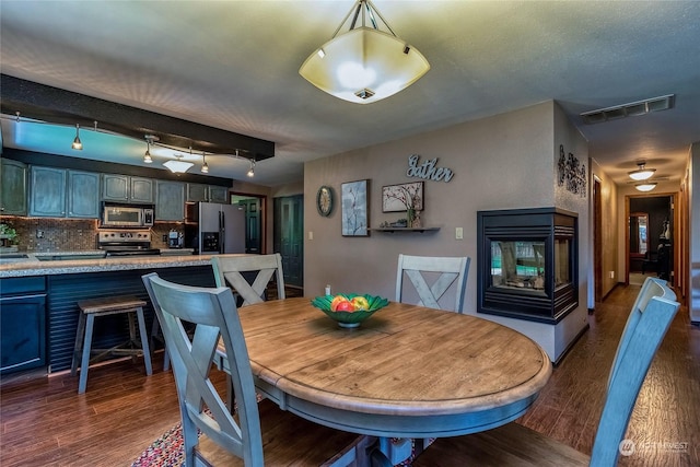 dining room featuring a multi sided fireplace and dark hardwood / wood-style flooring