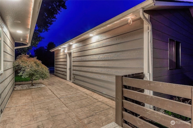 property exterior at night featuring a patio