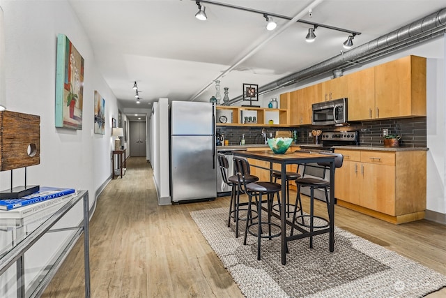 kitchen with tasteful backsplash, light wood-type flooring, track lighting, and stainless steel appliances