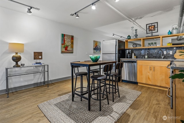 kitchen with decorative backsplash, light hardwood / wood-style flooring, appliances with stainless steel finishes, sink, and track lighting