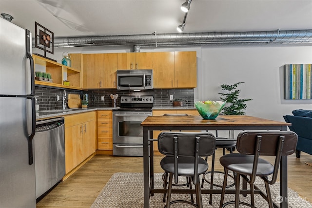 kitchen featuring rail lighting, appliances with stainless steel finishes, light hardwood / wood-style floors, light brown cabinetry, and decorative backsplash