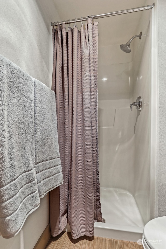 bathroom with walk in shower, hardwood / wood-style flooring, and toilet