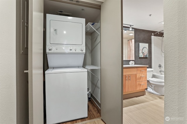 laundry room featuring light hardwood / wood-style flooring and stacked washer and clothes dryer