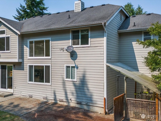 rear view of house with crawl space, a patio area, a shingled roof, and a chimney