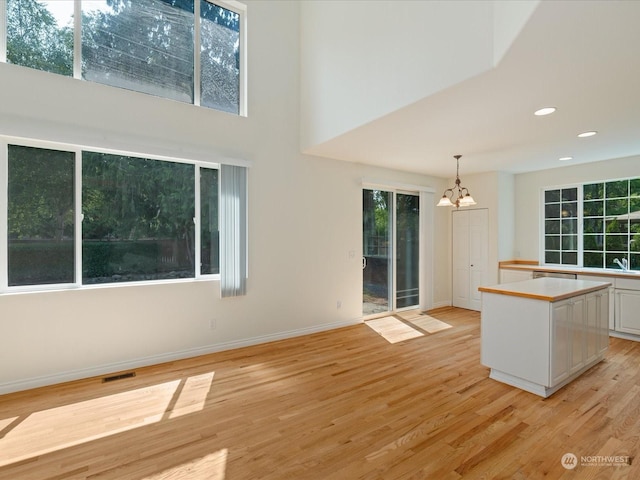 kitchen featuring a center island, pendant lighting, light countertops, light wood-style flooring, and white cabinets