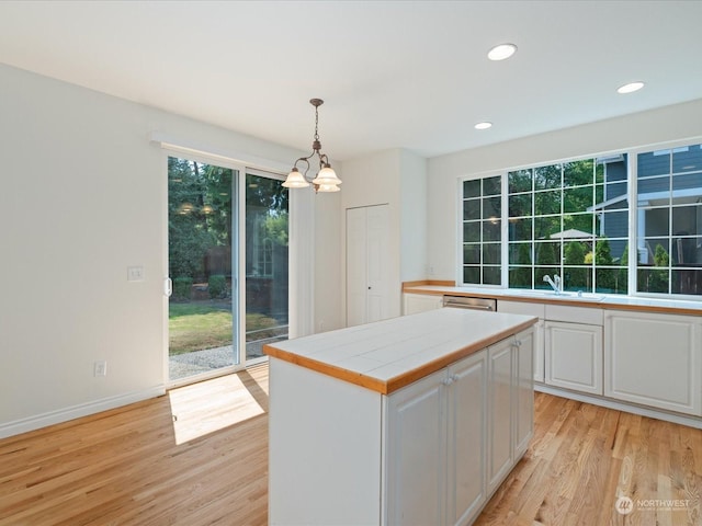 kitchen with a center island, white cabinetry, decorative light fixtures, and light wood finished floors