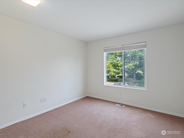 spare room featuring carpet floors, visible vents, and baseboards