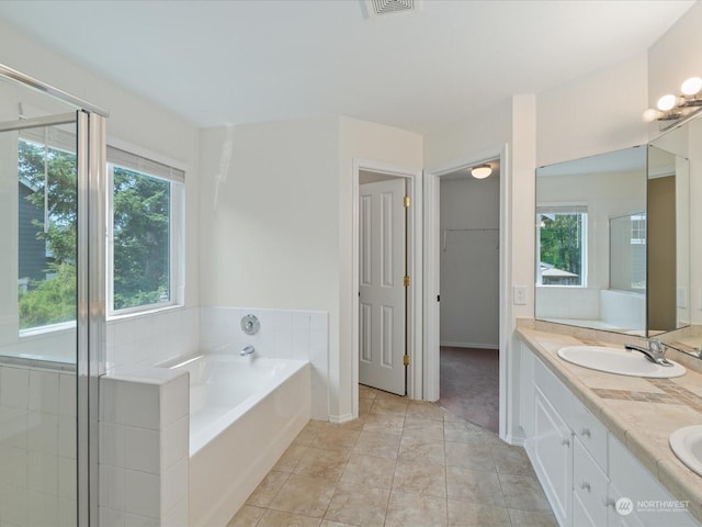 bathroom with double vanity, a sink, a spacious closet, a shower stall, and a bath