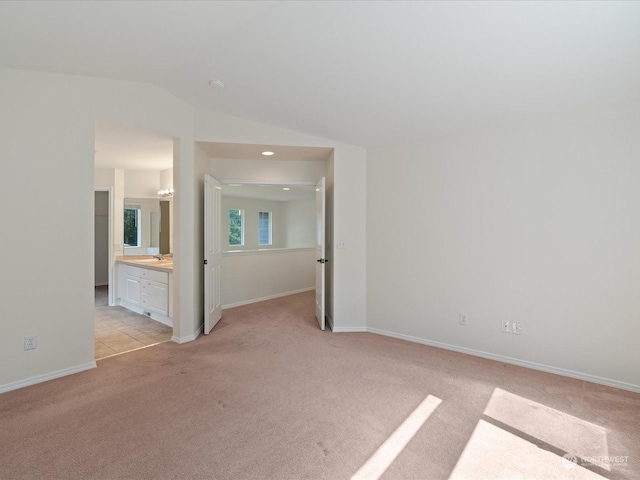 spare room with lofted ceiling, light colored carpet, and baseboards