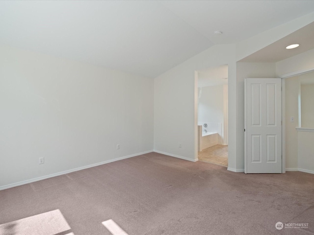 interior space with light carpet, vaulted ceiling, and baseboards