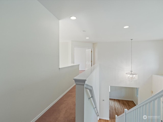 corridor with a notable chandelier, recessed lighting, an upstairs landing, baseboards, and carpet