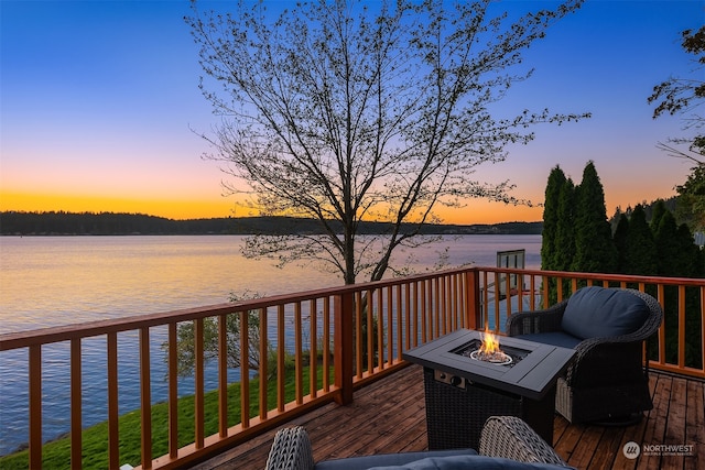 deck at dusk with a water view and a fire pit