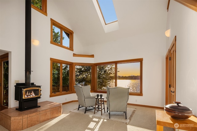 dining area with a skylight, light colored carpet, a wood stove, and a towering ceiling