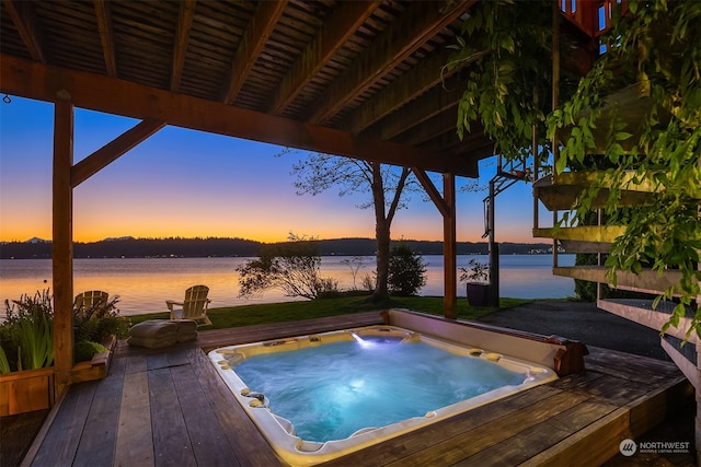 pool at dusk featuring a deck with water view