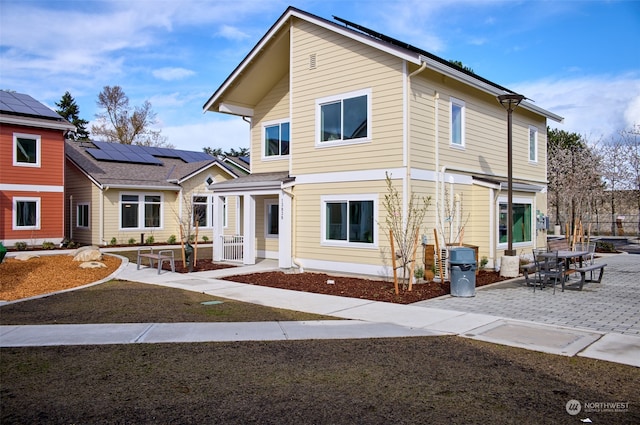 view of front of home with solar panels and a patio