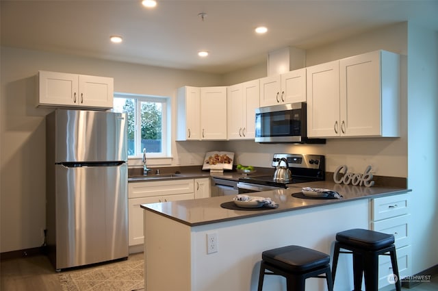 kitchen with appliances with stainless steel finishes, light hardwood / wood-style floors, sink, and white cabinetry