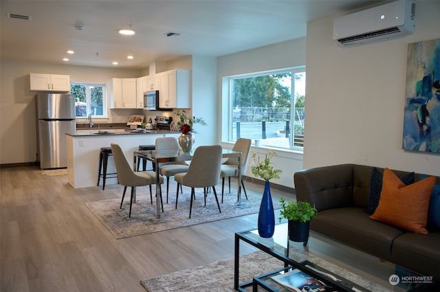 dining room with an AC wall unit and light wood-type flooring