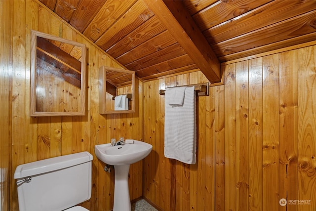 bathroom with lofted ceiling with beams, wood walls, wooden ceiling, and toilet