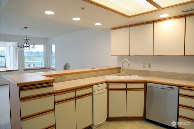 kitchen featuring recessed lighting, light countertops, stainless steel dishwasher, a sink, and a peninsula