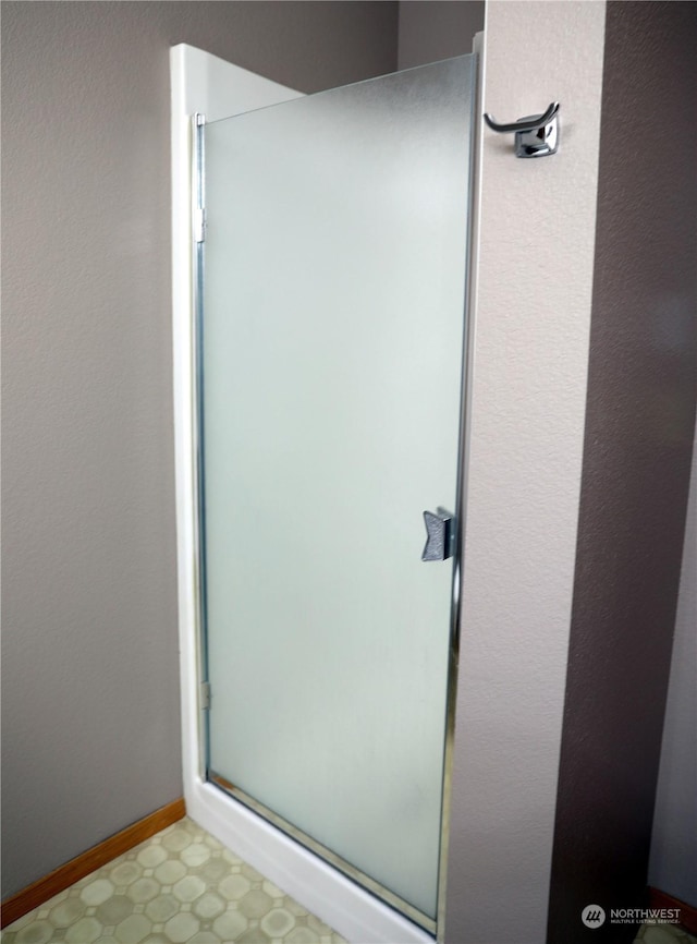 full bath with a stall shower, baseboards, and tile patterned floors