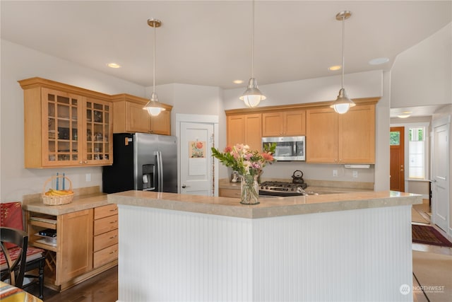 kitchen with appliances with stainless steel finishes, dark hardwood / wood-style flooring, light brown cabinetry, and hanging light fixtures