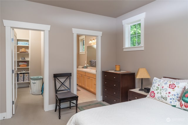 bedroom with ensuite bathroom and light colored carpet