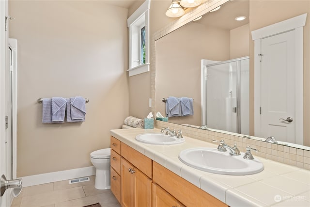 bathroom with tile patterned floors, double vanity, a shower with door, and toilet