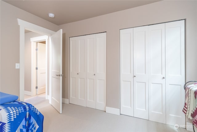 bedroom featuring multiple closets and light colored carpet